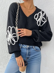 Detailed view of white floral embroidery on a black V-neck knit sweater for women