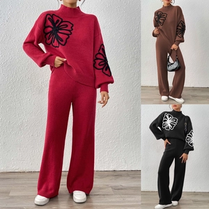Detail of floral embroidery on high-neck lantern sleeve sweater and wide-leg knit pants