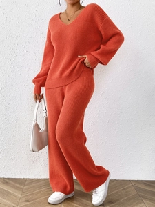 Detail of orange V-neck knit sweater and wide-leg pants showing ribbed texture