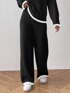 Dettaglio delle strisce bianche a contrasto sui pantaloni in maglia nera e sui polsini