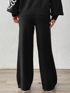 Women's black knit set featuring high-waisted wide-leg pants and floral sleeve detail