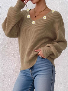 Detailansicht eines V-Ausschnitt-Strickpullovers mit weißen Gänseblümchen-Applikationen