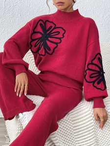 Detailed view of dark red knit sweater featuring 3D black floral ribbon embroidery design