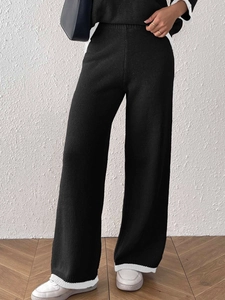 Dettaglio dei pantaloni in maglia a vita alta con bordo a contrasto bianco e texture