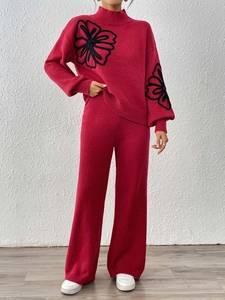 Detail of red knit sweater with black floral embroidery and high neck lantern sleeves
