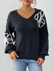 Detail of white abstract floral embroidery on black V-neck knitted sweater fabric