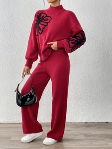 Detail of burgundy knit sweater with high neck and 3D black flower ribbon embroidery