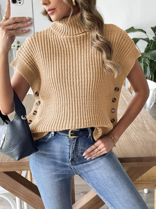 Dettaglio del gilet in maglia color cammello con collo alto e bottoni in ambra laterali