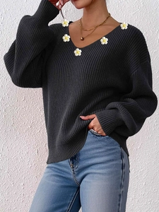 Detailaufnahme von schwarzem V-Ausschnitt-Strickpullover mit weißen 3D-Blumenapplikationen