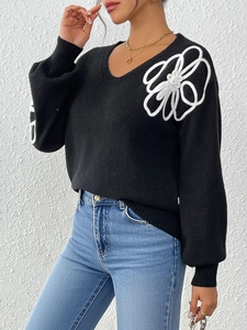 Detail of white floral ribbon embroidery on a black V-neck knit sweater for women