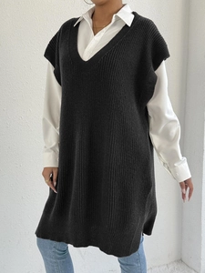 Dettaglio del gilet nero in maglia con scollo a V su camicia bianca e jeans blu