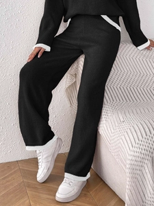 Dettaglio del set due pezzi in maglia nera con polsini a costine bianche a contrasto