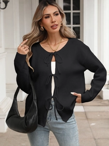 Detail of black knit cardigan featuring unique front bow tie closures and sleeve texture