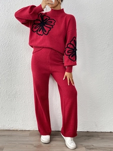 Red knit two-piece set featuring oversized black floral embroidery on sweater and pants