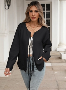 Close-up of black knit cardigan with bow tie-front closure and textured fabric detail