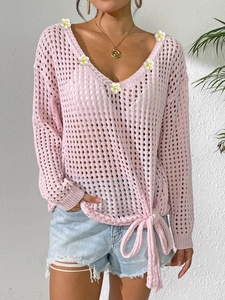 Detailed close-up of V-neck crochet sweater with floral appliques and lace-up bow hem