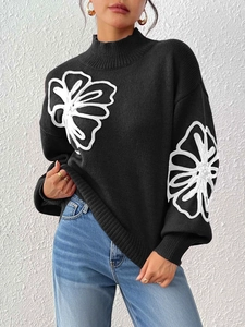 Detail of black mock neck sweater featuring white floral embroidery and lantern sleeves