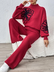 Detail of red knit sweater with black floral embroidery and matching wide-leg trousers