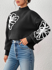 Close-up of white 3D floral embroidery on a black knit sweater with high neck design