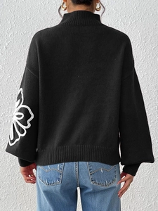 Detailed rear view of black sweater with white floral embroidery on the lantern sleeve