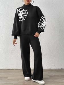 Detail of floral embroidery on black knitted sweater with elegant high collar