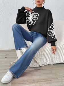 Detail of black knit sweater featuring white floral ribbon embroidery and lantern sleeves