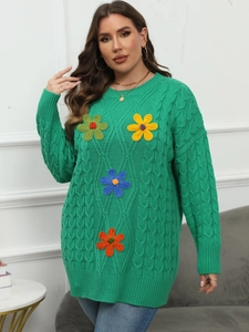 Close-up of green cable-knit plus size sweater featuring colorful floral embroidery details