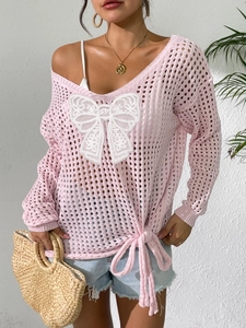 Detail eines rosa hohlgestrickten Pullovers mit weißer Spitzen-Schleife und Bindeband
