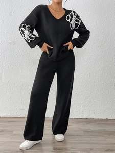 Détail du pull en maille noir à col en V avec une élégante broderie de fleurs en 3D