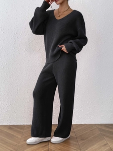 Detail of dark grey V-neck knit sweater and wide-leg trousers set with thick ribbed texture