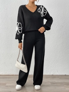 Détail de la broderie florale blanche sur l'ensemble en tricot noir avec col en V pour femme