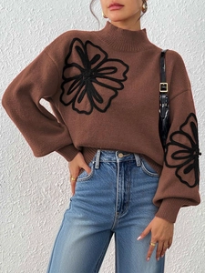 Detail of brown turtleneck sweater featuring large black floral embroidery and knit texture