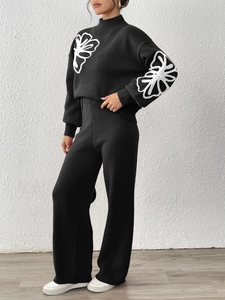 Detail of black knit sweater with white floral embroidery and high neck for women