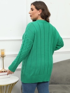 Detail of green knitted sweater featuring cable knit sleeves and ribbed back texture