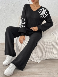 Détail de la broderie sur la manche du pull en tricot noir col V et du pantalon large