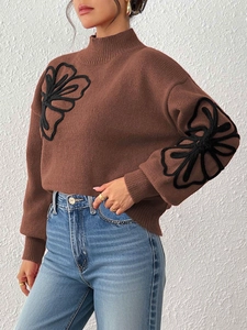 Detail of brown knit sweater featuring black 3D floral embroidery and lantern sleeves