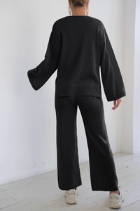Detail view of the knitted texture and loose fit of the black sweater and wide leg pants