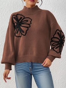 Detail of dark brown high-neck sweater featuring black rope floral embroidery and ribbed cuffs
