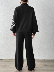 Detail of white flower embroidery on black lantern sleeves of a knit sweater set
