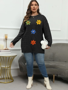 Detail of cable knit pattern and colorful crochet flower appliques on black sweater