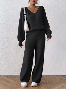 Close-up of black knit set featuring vertical ribbed texture on V-neck sweater and wide pants