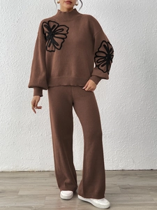 Detailed view of black floral embroidery on dark brown knit sweater and trousers set
