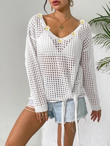Detailed close-up of white crochet top with 3D daisy flowers and side drawstring ribbons