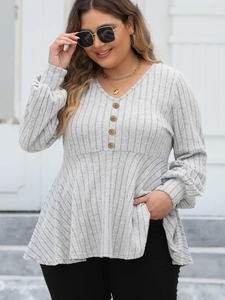 Detailed close-up of vertical ribbed fabric texture and golden decorative buttons on V-neck top