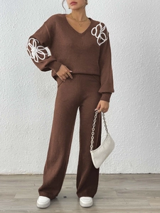 Détail de la broderie florale blanche sur le pull en maille marron et le pantalon