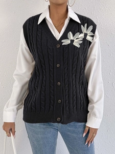 Detail of cable knit vest with 3D white mesh floral appliques and layered styling