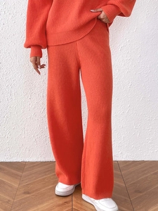 Detail of high-waisted orange-red rib-knit wide leg trousers with vertical texture