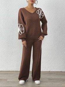 Détail de broderie florale blanche sur un ensemble en tricot marron avec col en V pour femme