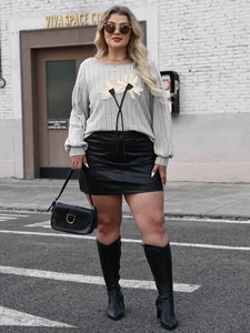 Detail of grey daisy print knit top paired with a black faux leather mini skirt