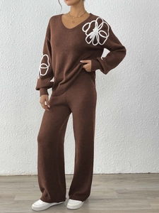 Détail de la broderie florale blanche sur l'ensemble en maille marron à col en V